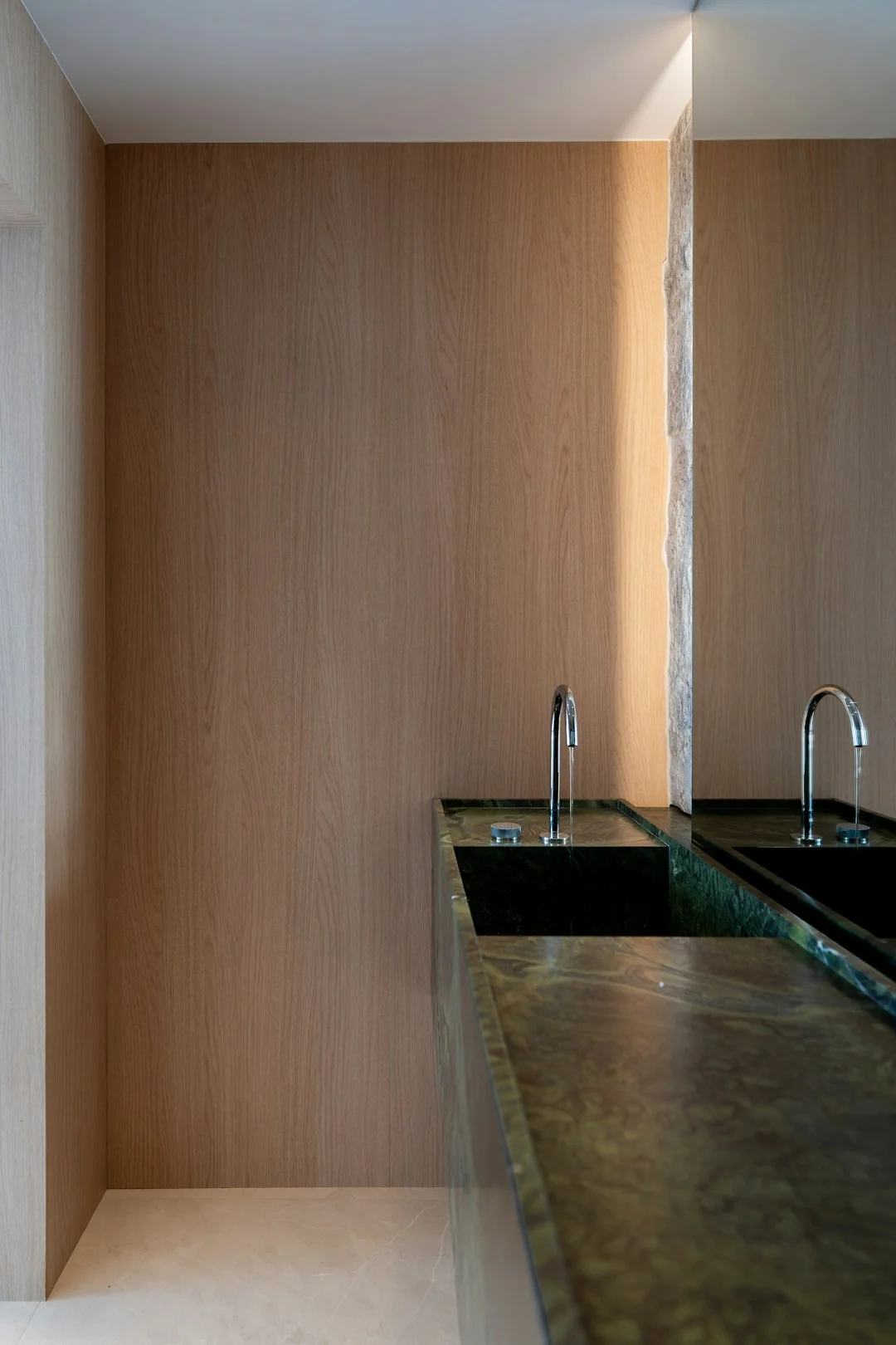 Zaměstnanec hotelu držící ručníky v luxusní koupelně s elegantním zařízením.